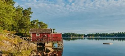 Rotes Holzhaus an einem See in Skandinavien