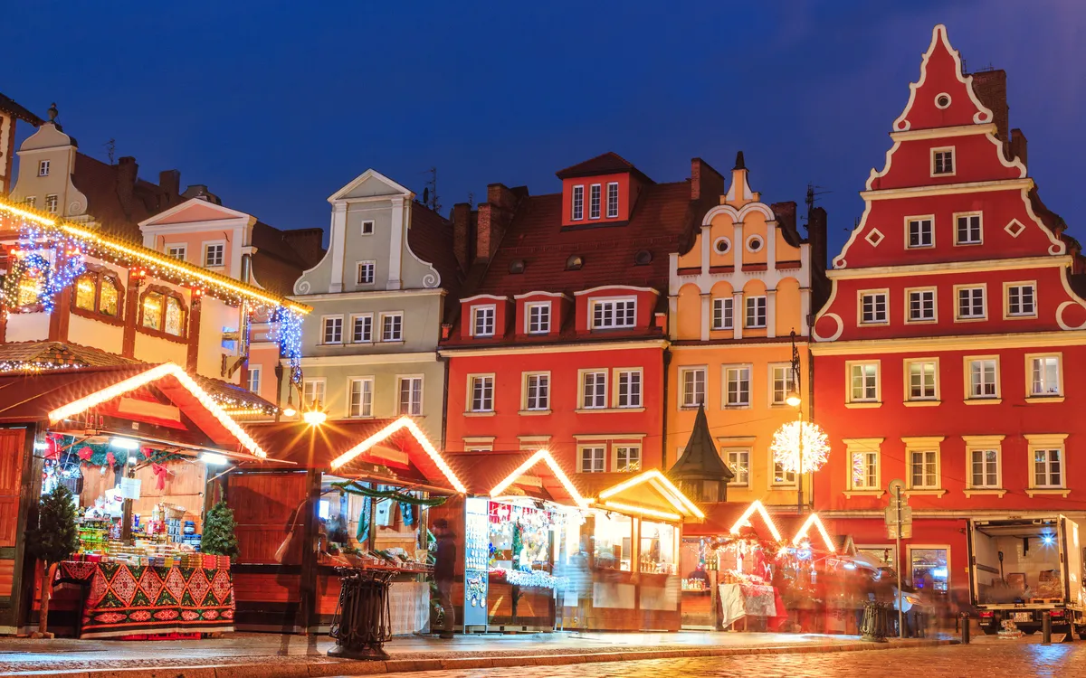 Beleuchtete Fachwerkhäuser an einem Weihnachtsmarkt bei Nacht.