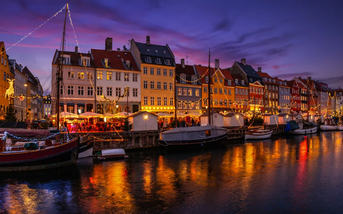 Abendstimmung mit beleuchteten Häusern und Booten an einem Kanal.