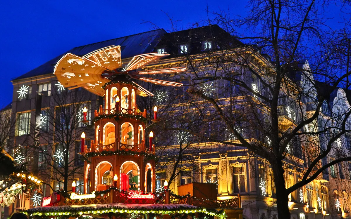 Weihnachtsmarkt mit beleuchtetem Karussell und Bäumen bei Dämmerung.