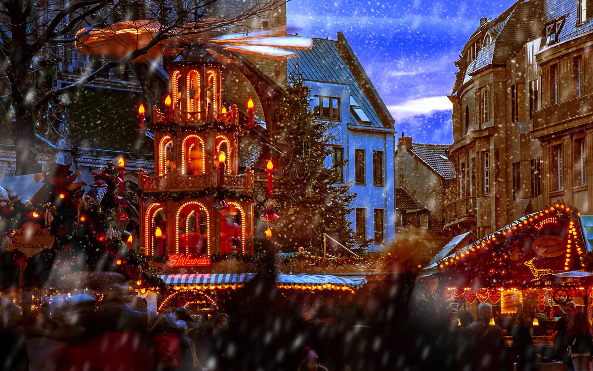 Voller Weihnachtsmarkt mit festlichen Lichtern und Menschen im Schnee.