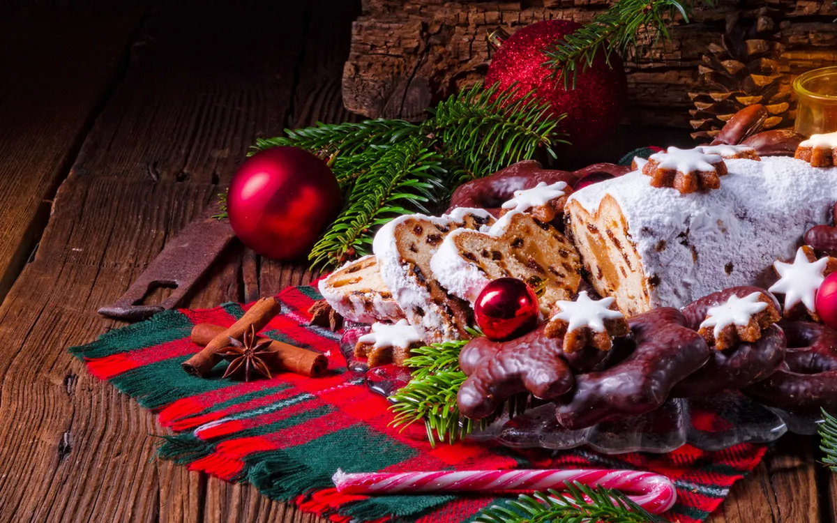 Weihnachtliche Lebkuchen und Christstollen auf Holztisch mit Dekoration.