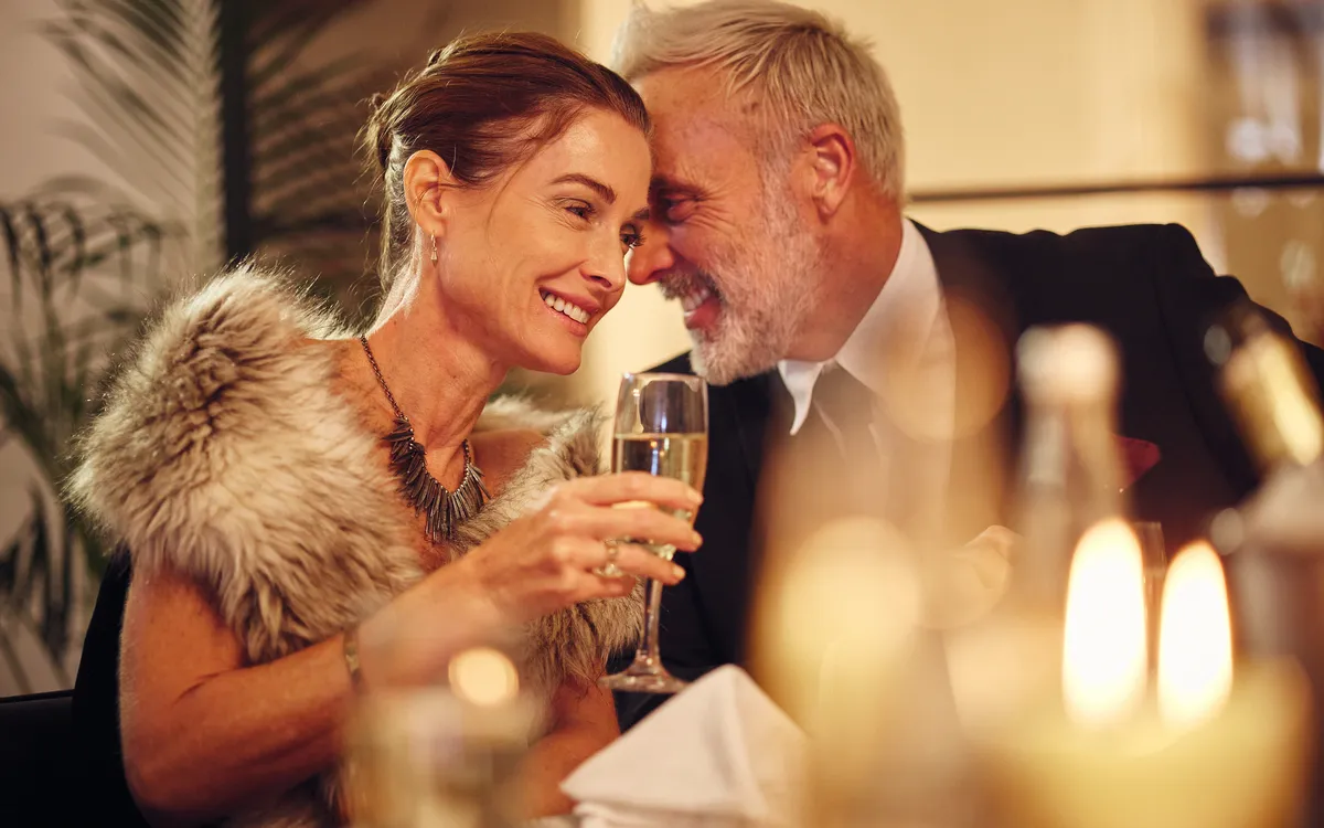 Älteres Paar genießt ein Abendessen mit Champagner in festlicher Atmosphäre.