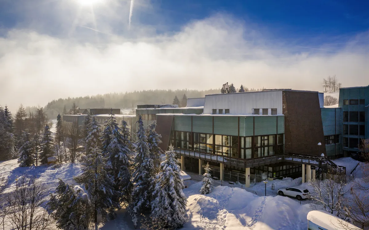 Außenansicht des Ahorn Waldhotels Altenberg im Winter mit Schnee und Bäumen.