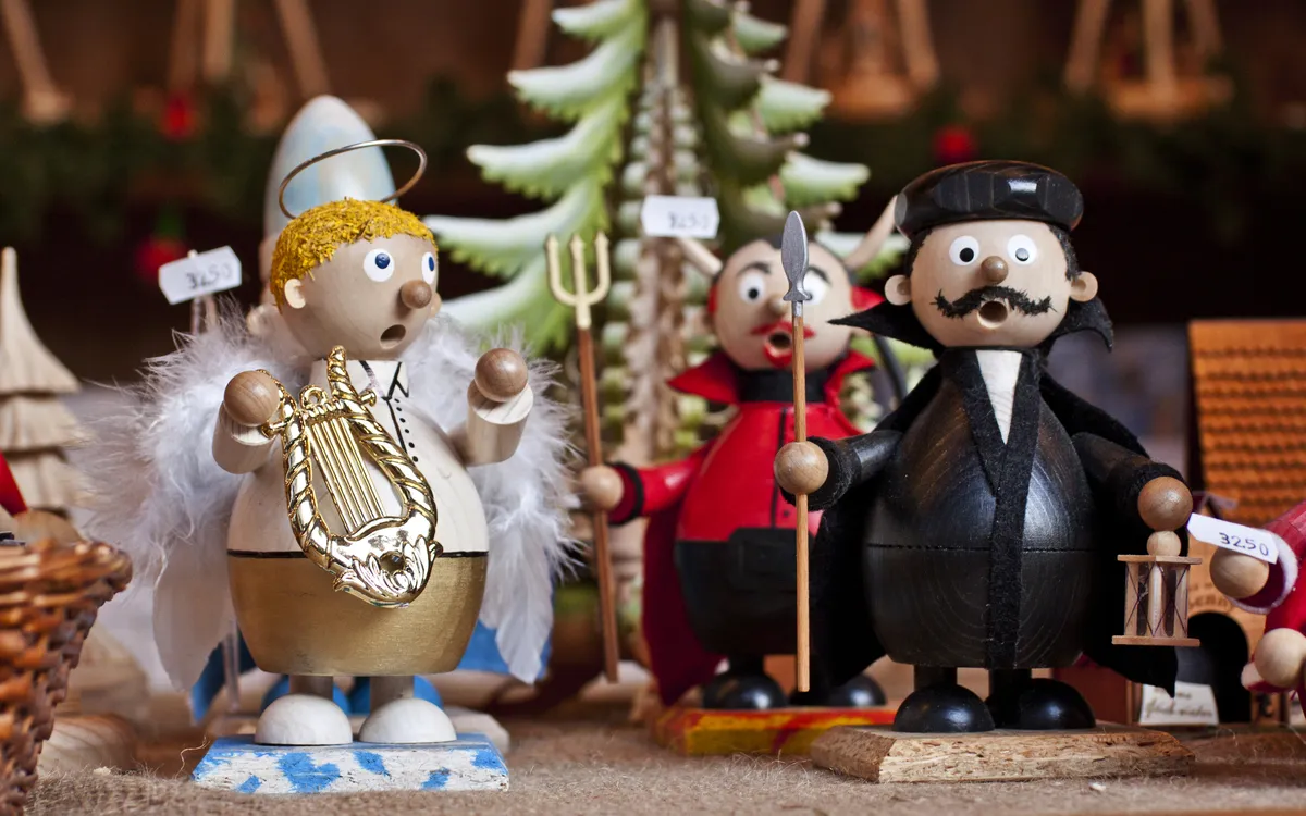 Holzfiguren von Engeln und Figuren in Weihnachtskostümen auf einem Markt.