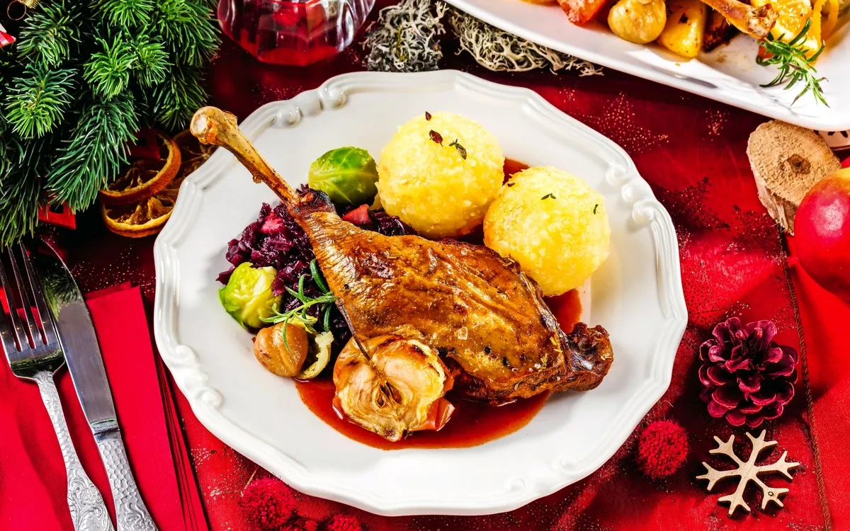Festlich gedeckter Tisch mit Gänsebraten, Knödel und Rotkohl.