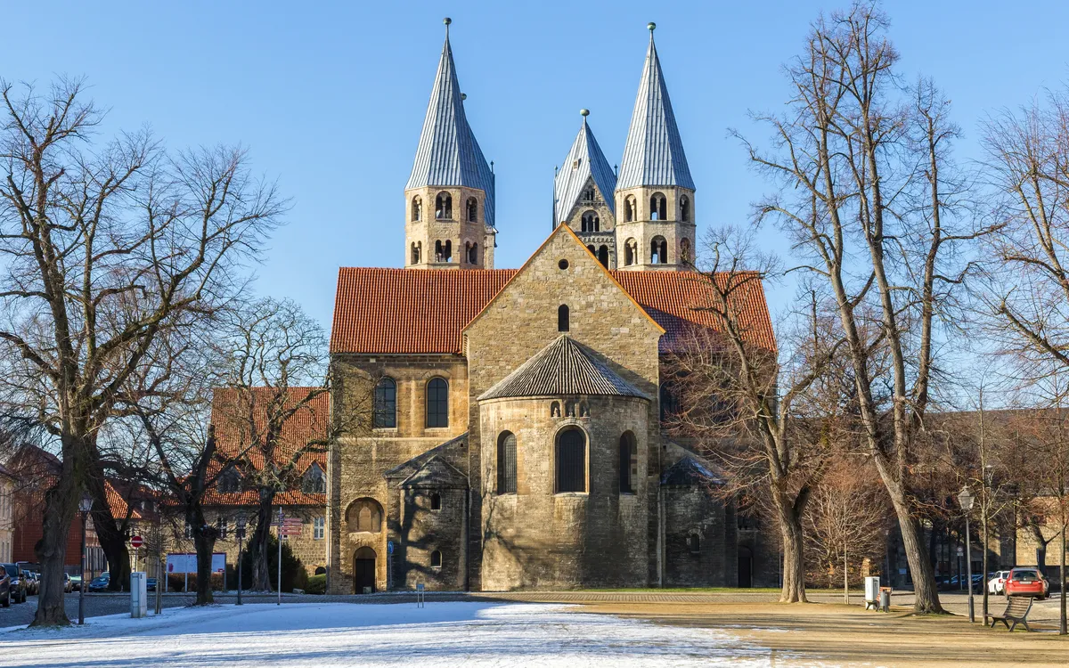 Kirche mit zwei Türmen und schneebedecktem Vorplatz an einem sonnigen Tag.