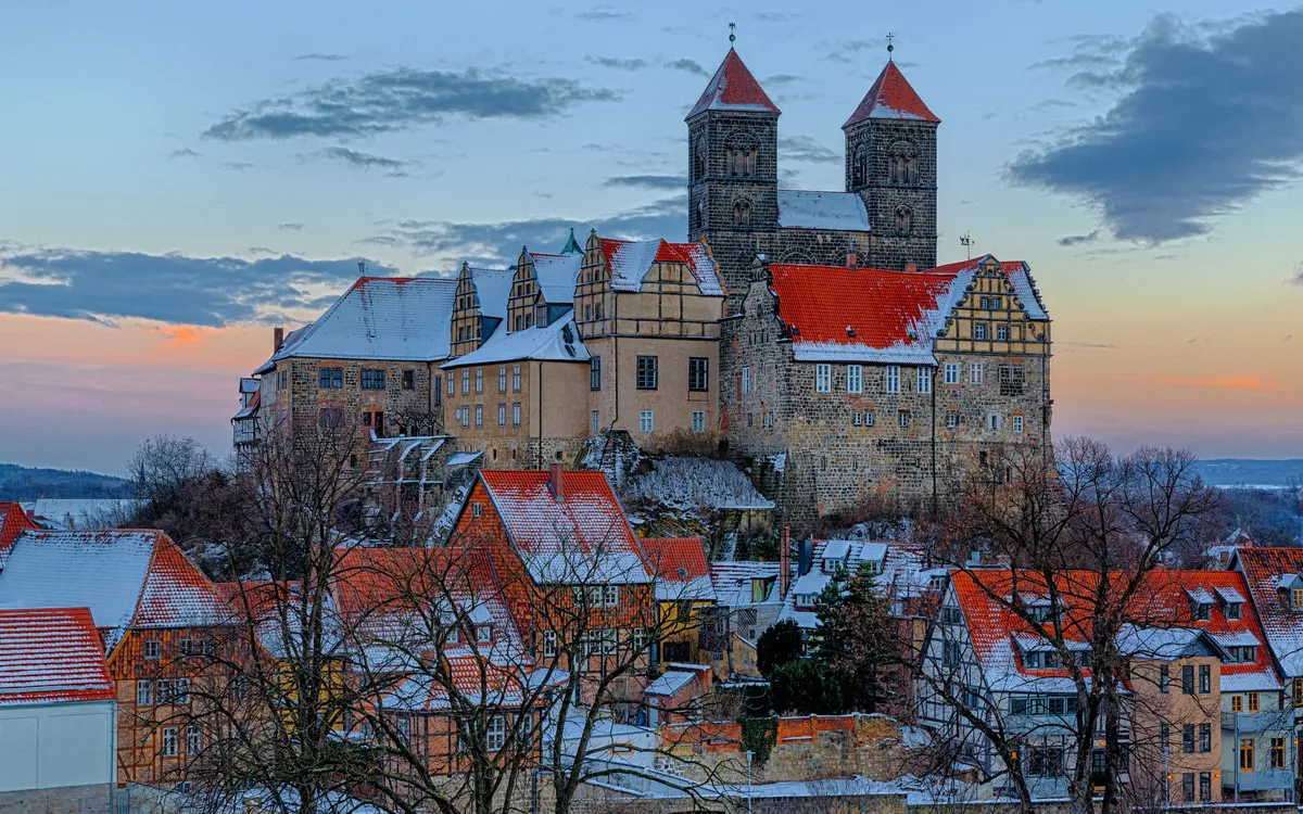 Eine Burg auf einem Hügel mit schneebedeckten Dächern im Winter.