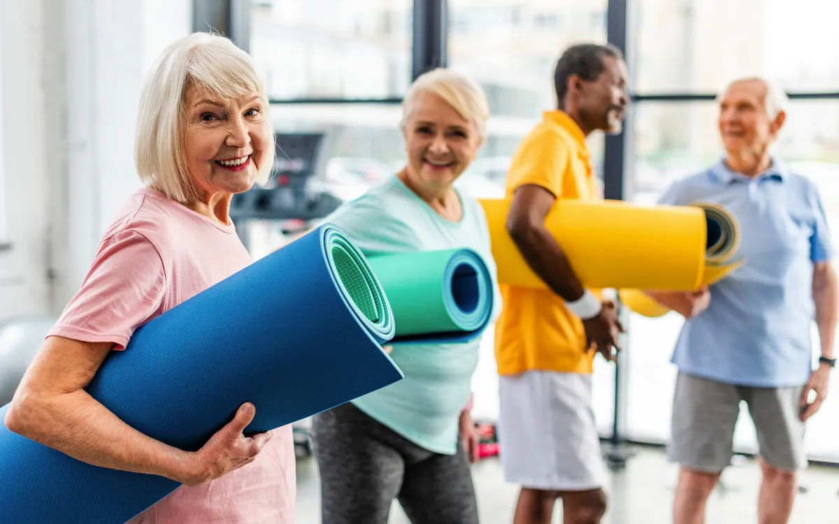 Ältere Menschen halten Yogamatten im Fitnessstudio.
