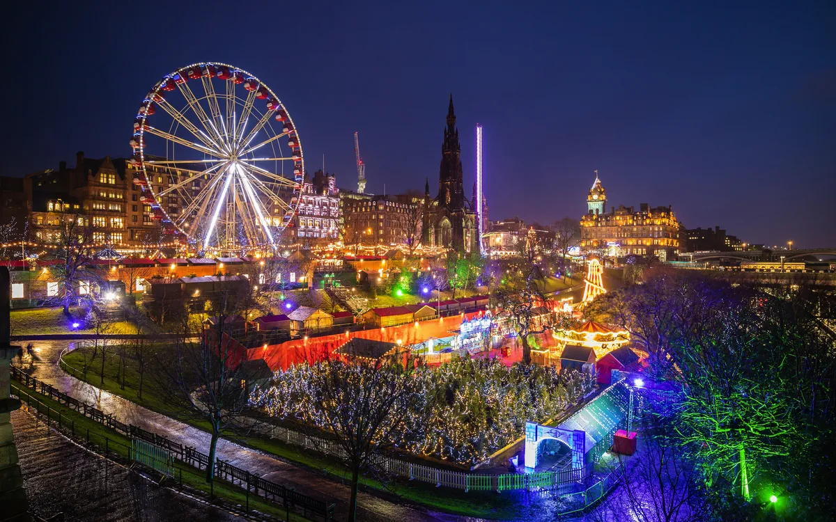 Rummelplatz bei Nacht mit beleuchtetem Riesenrad und Ständen.