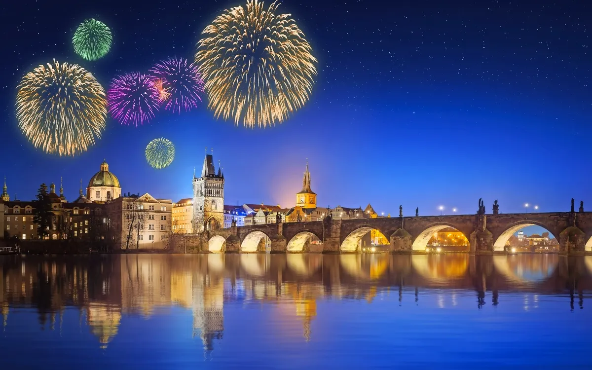 Feuerwerk über nächtlicher Stadtlandschaft mit Brücke und Wasser reflektiert