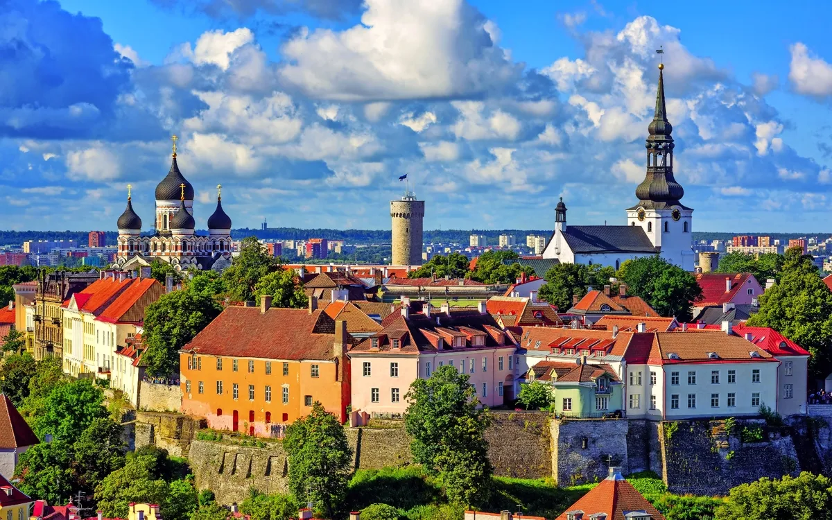Stadtansicht mit Türmen und Kirchen unter blauem Himmel und Wolken.