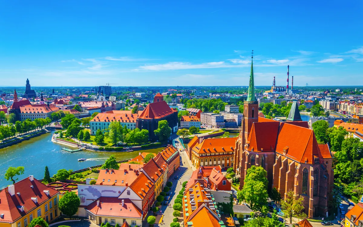 Panoramablick auf Breslau mit der Skyline, dem Breslauer Dom (Kathedrale St. Johannes der Täufer) und der Oder, umgeben von der Dominsel bei klarem Himmel.