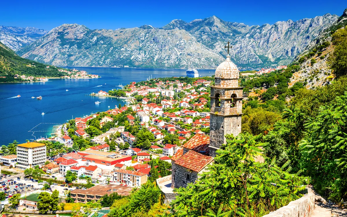 Mittelalterlicher Glockenturm mit Blick auf Küstenstadt Kotor, umgeben von Bergen und Meer.