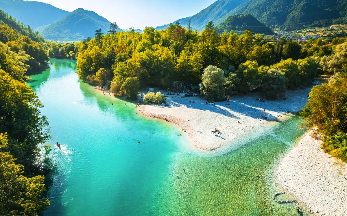 Fluss mit türkisfarbenem Wasser in einer grünen Berglandschaft.