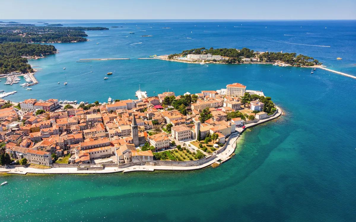 Luftaufnahme einer Küstenstadt mit historischen Gebäuden und blauem Meer.