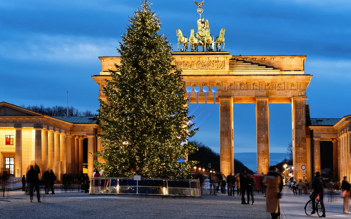 Brandenburger Tor mit Weihnachtsbaum bei Nacht.
