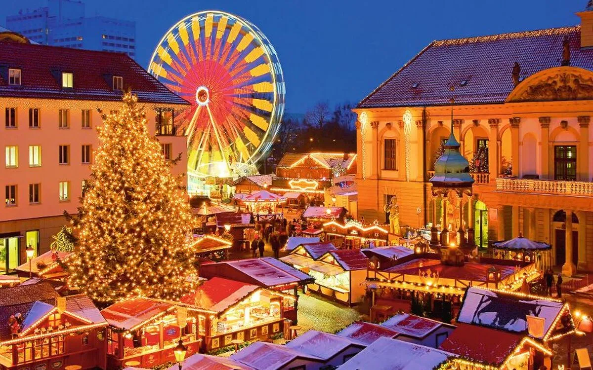 Weihnachtsmarkt mit beleuchtetem Riesenrad und geschmücktem Weihnachtsbaum bei Abenddämmerung