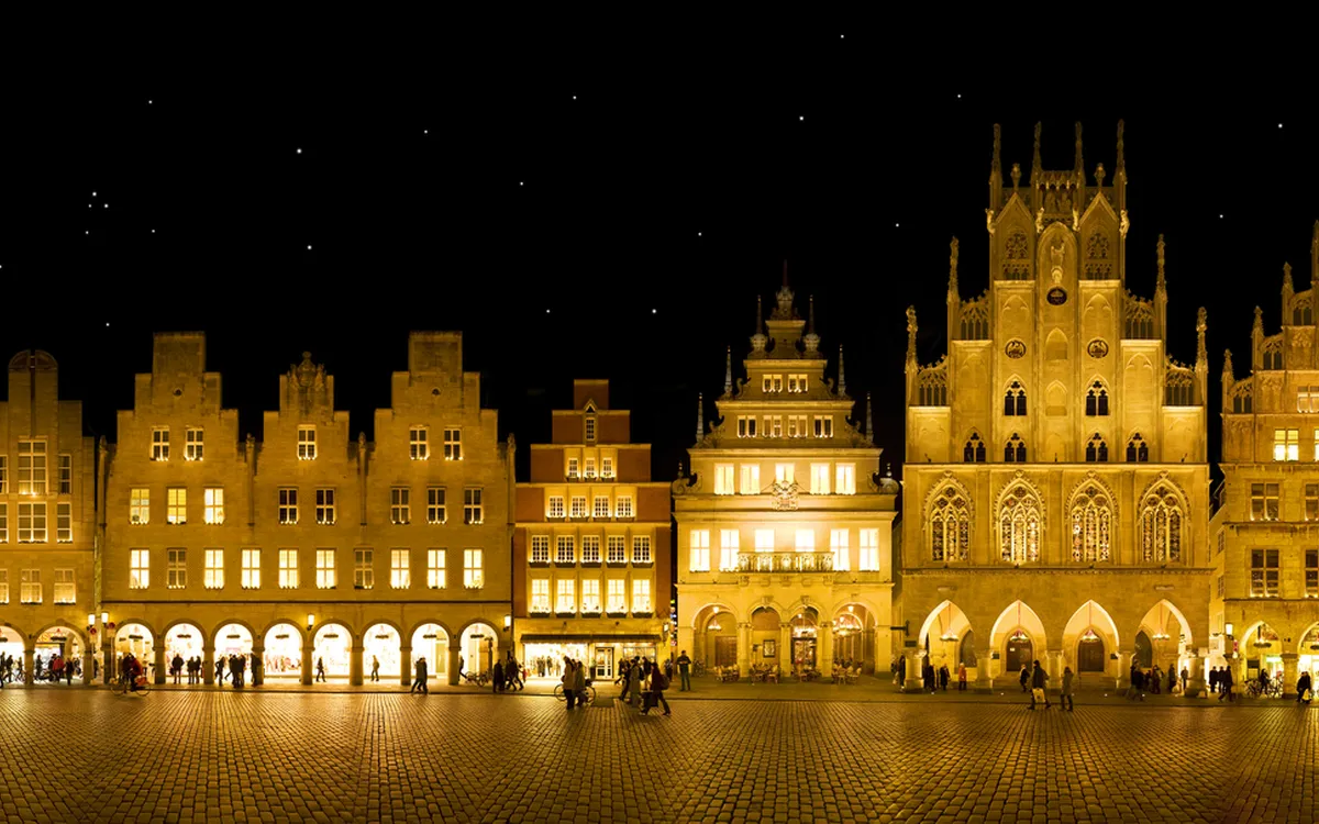 Beleuchtete historische Gebäude bei Nacht mit Sternenhimmel und Vollmond.