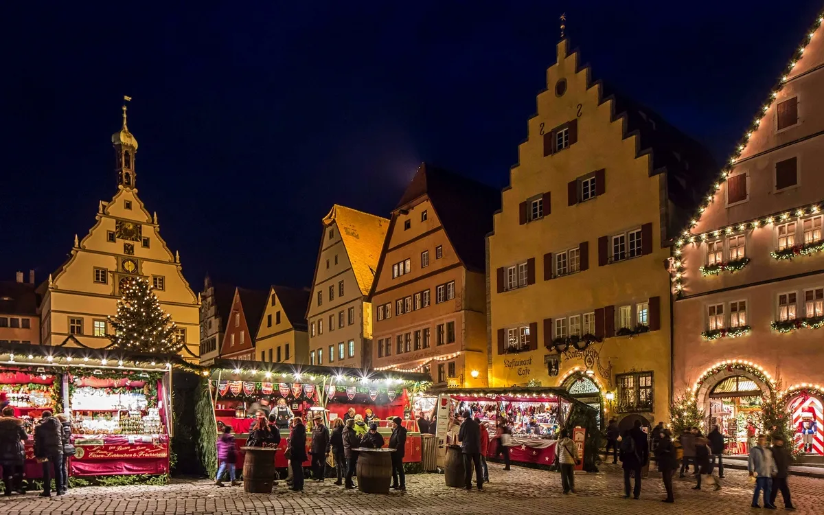 Stände auf dem Reiterlesmarkt in Rothenburg o.d. Tauber bei Nacht, belebt und festlich erleuchtet.