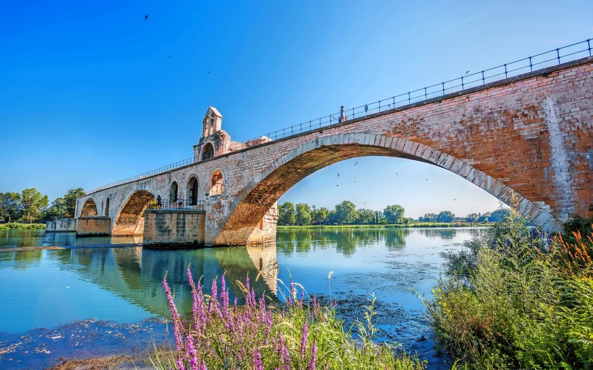 Alte Steinbrücke über einen Fluss mit klarem blauen Himmel.