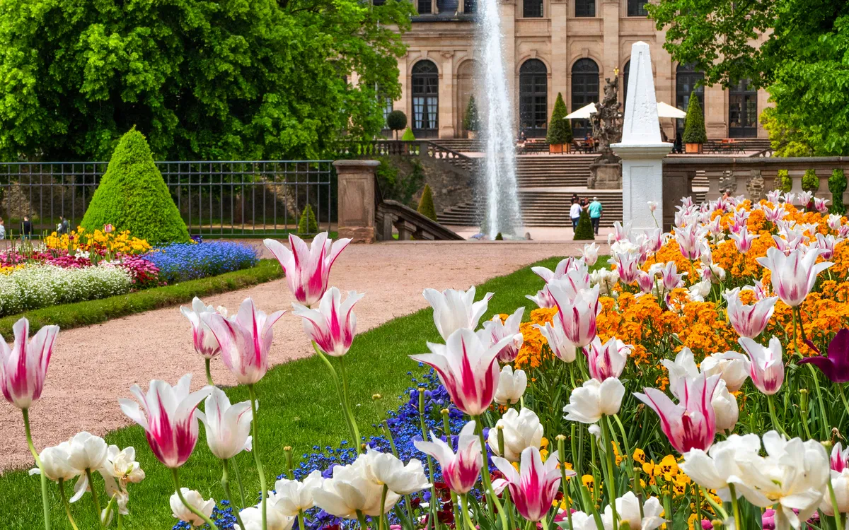 Blumenbeet und Brunnen im Schlossgarten des barocken Stadtschlosses in Fulda, Hessen.