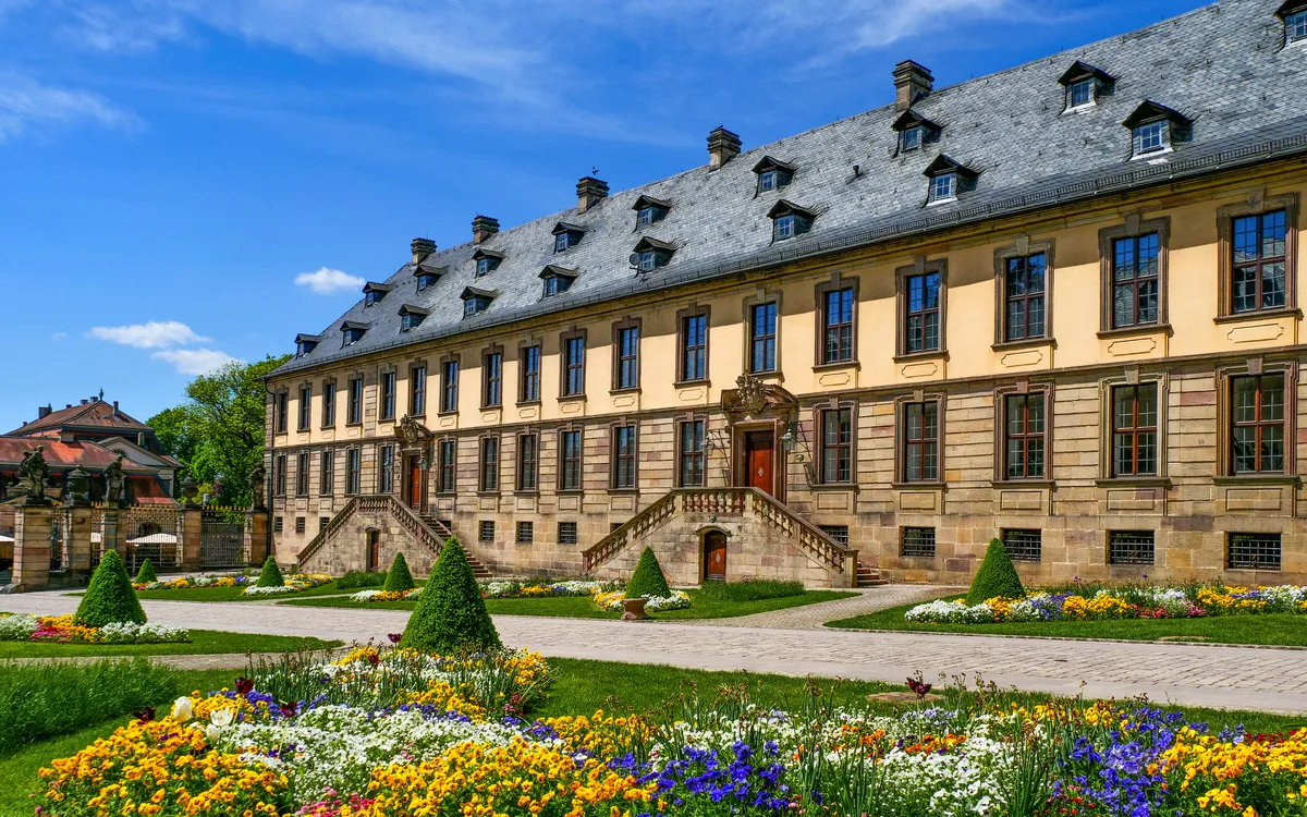 Historisches Gebäude mit Garten und blauem Himmel.