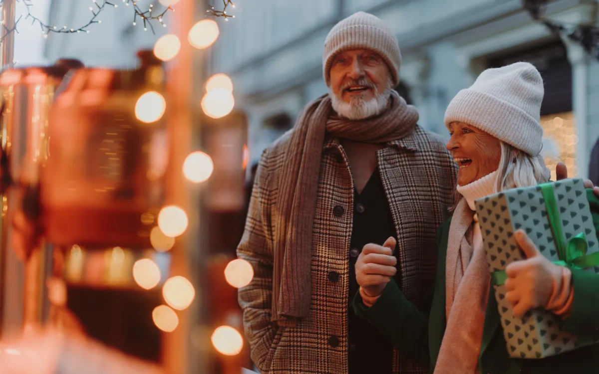 Älteres Paar mit Geschenken auf einem festlichen Markt im Winter.