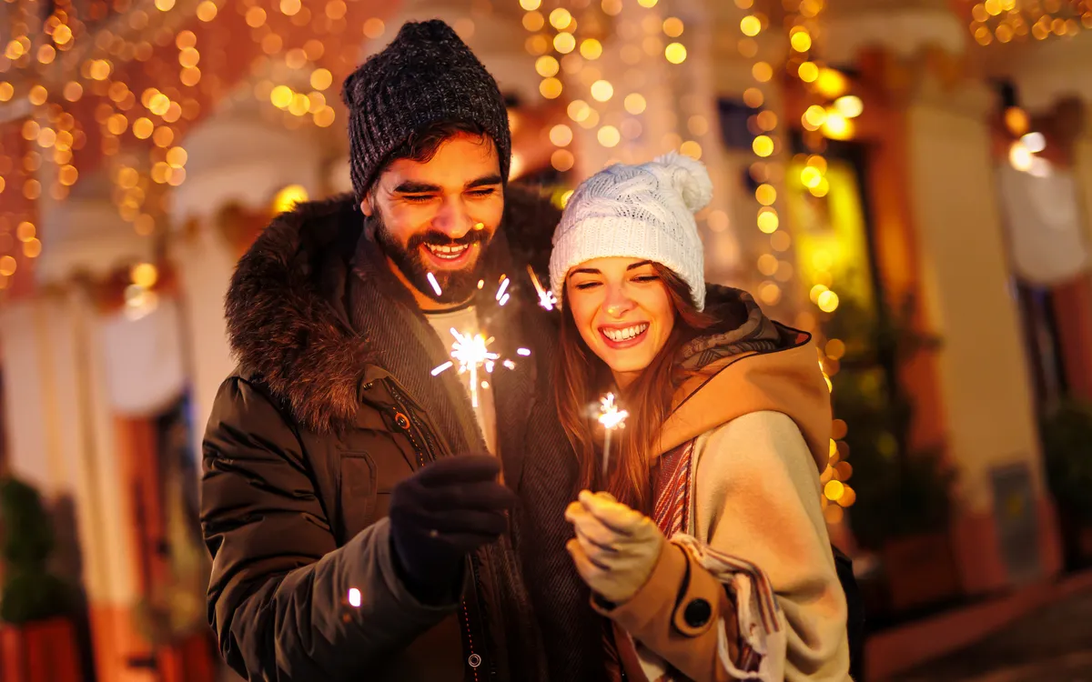 Paar hält Wunderkerzen auf einem festlichen Weihnachtsmarkt.
