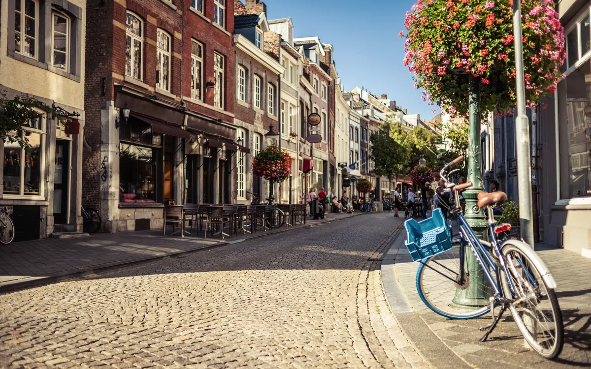 Maastrichter Straßen mit Kopfsteinpflaster, Fahrrad und Blumen im Sommer.