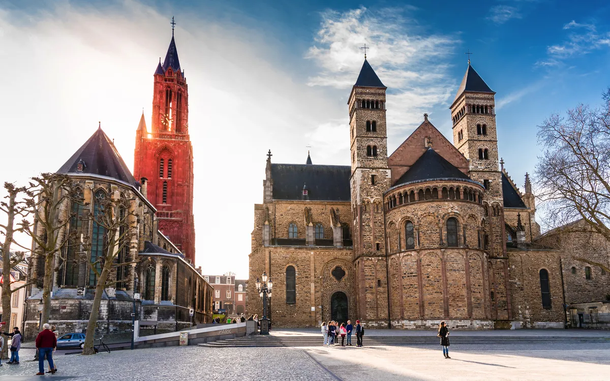 Kirche mit zwei Türmen und rotem Glockenturm bei klarem Himmel.