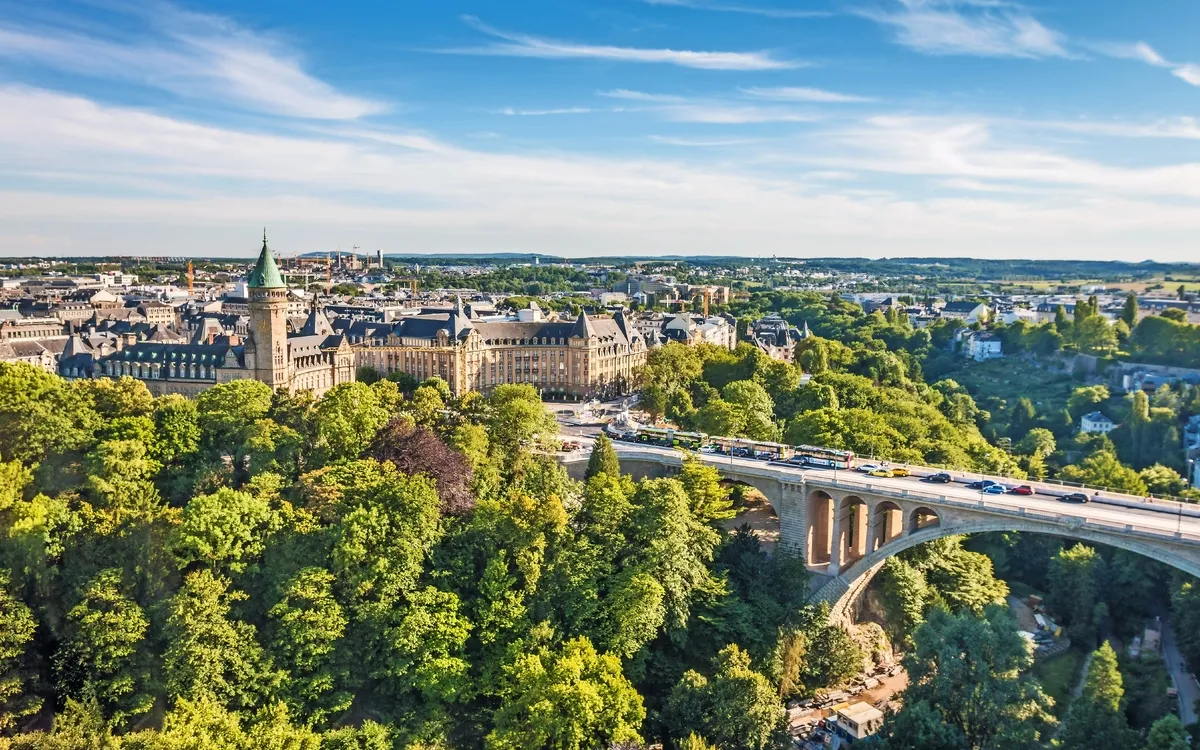Stadtansicht mit Brücke und historischer Architektur, umgeben von Bäumen.
